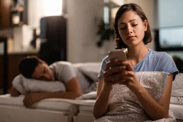 Wife checks her husband's phone while he sleeps