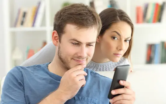 Wife peeks at husband's phone from behind