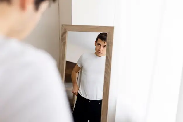 Boyfriend is looking in the mirror and adjusting his clothes