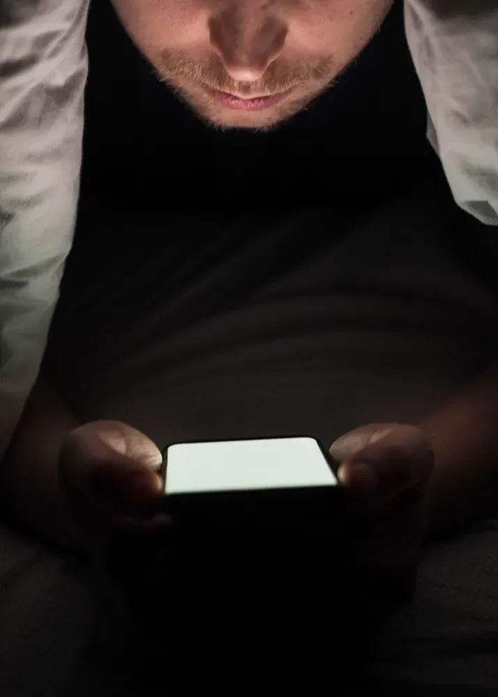 Husband under sheets searching spouse’s phone