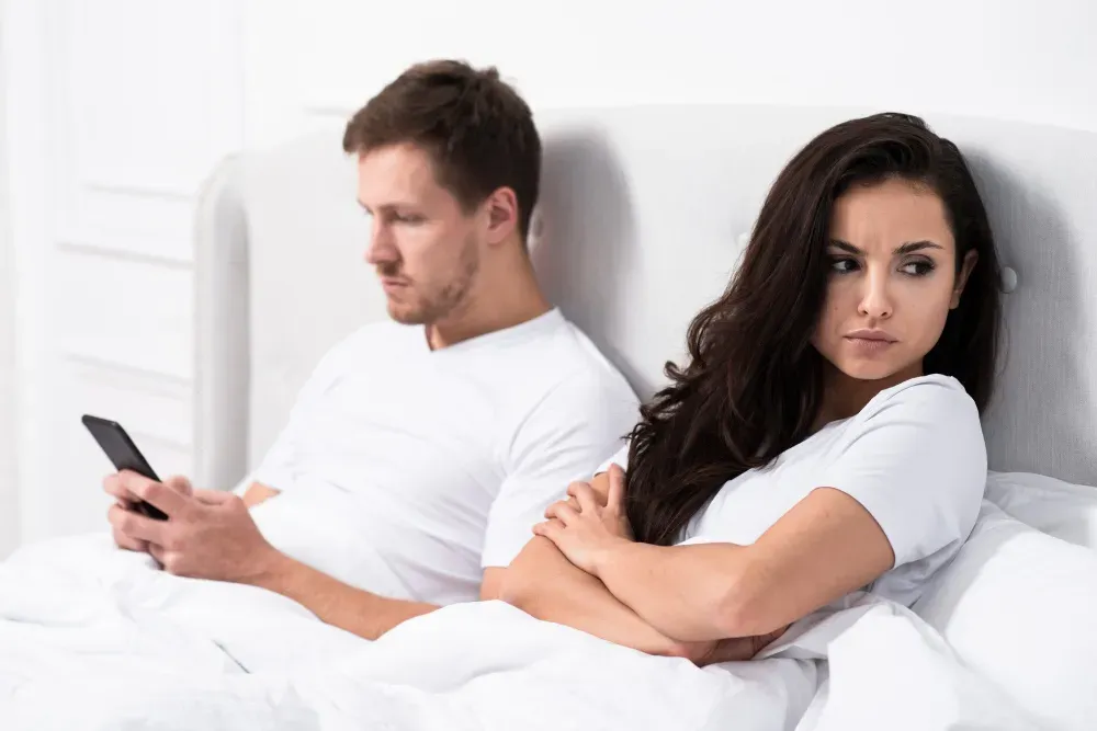 Wife annoyed with husband looking at his phone in bed