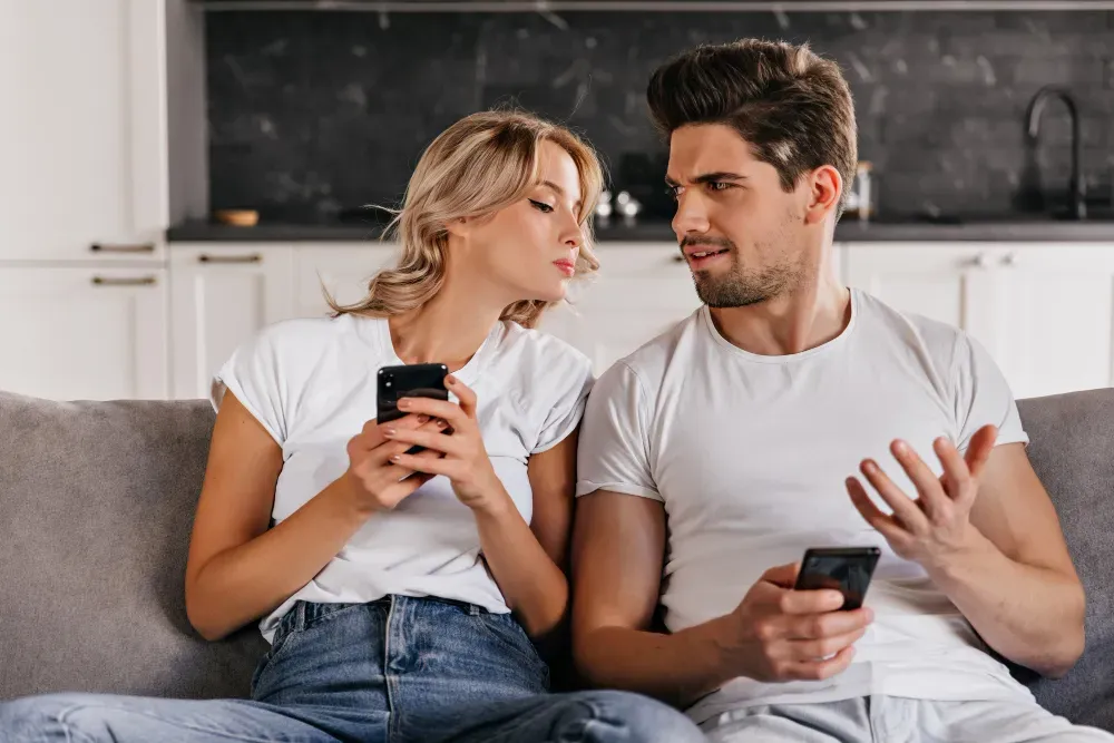 Woman sitting next to husband trying to get his messages